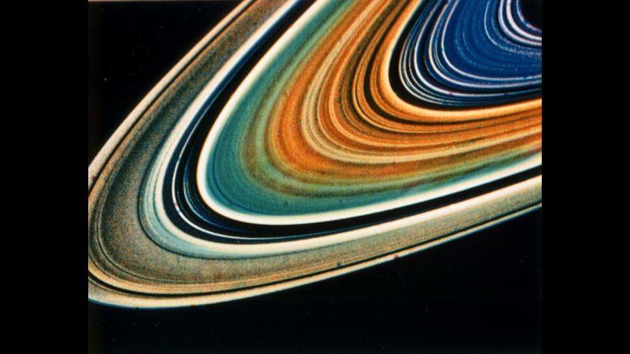 1981年8月17日，旅行者2号在距离土星890万公里处拍摄到的土星环系统的彩色增强图像。土星环之间的颜色变化表明了土星环系统的不同部分的化学成份变化。来源：NASA