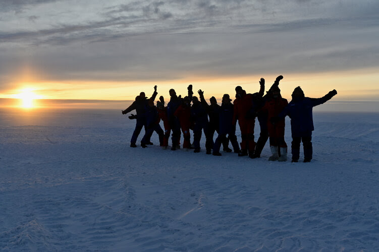 人们在南极洲的雪地里，映衬在他们身后的夕阳下。来源：ESA